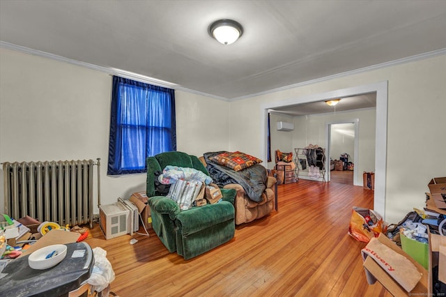 living area with hardwood / wood-style floors, crown molding, and radiator heating unit