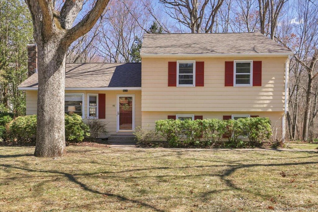 tri-level home featuring a shingled roof, a chimney, and a front yard