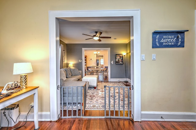 living room with baseboards, ceiling fan, wood finished floors, and crown molding