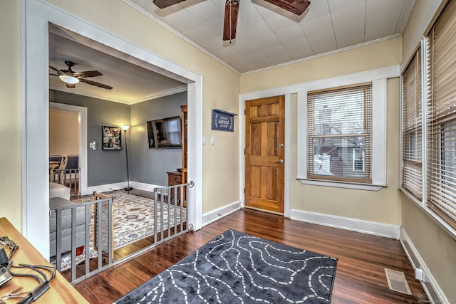 foyer entrance with ornamental molding, baseboards, visible vents, ceiling fan, and wood finished floors