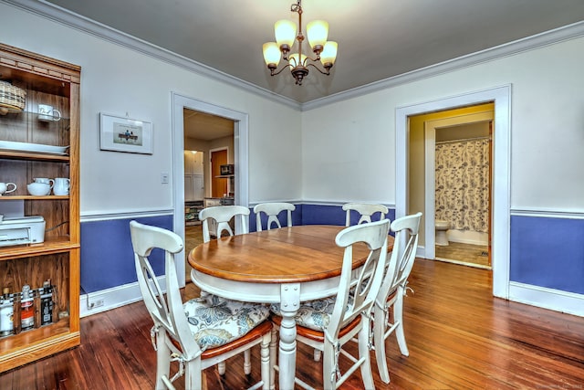 dining room featuring a notable chandelier, crown molding, baseboards, and wood finished floors