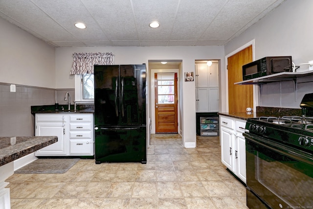 kitchen featuring white cabinetry, a healthy amount of sunlight, a sink, and black appliances