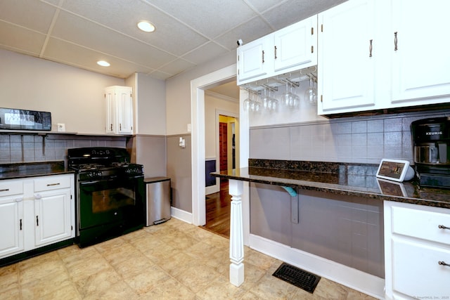 kitchen with white cabinetry, dark stone counters, black appliances, and visible vents