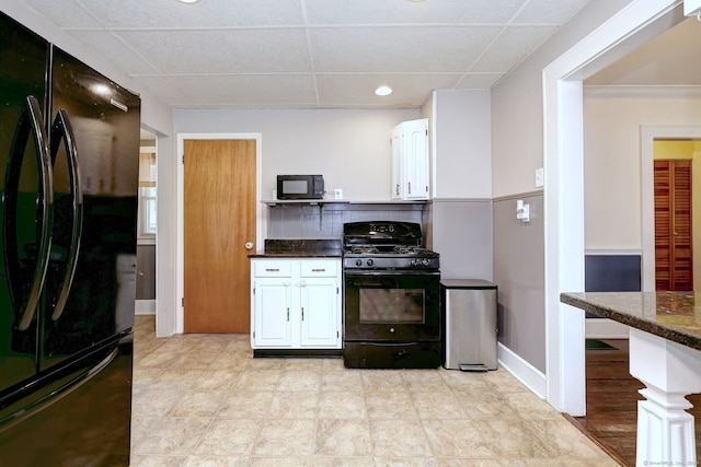 kitchen with white cabinets, dark countertops, black appliances, and a paneled ceiling