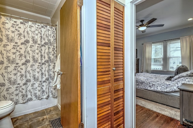 bathroom with a closet, crown molding, toilet, shower / tub combo, and ceiling fan