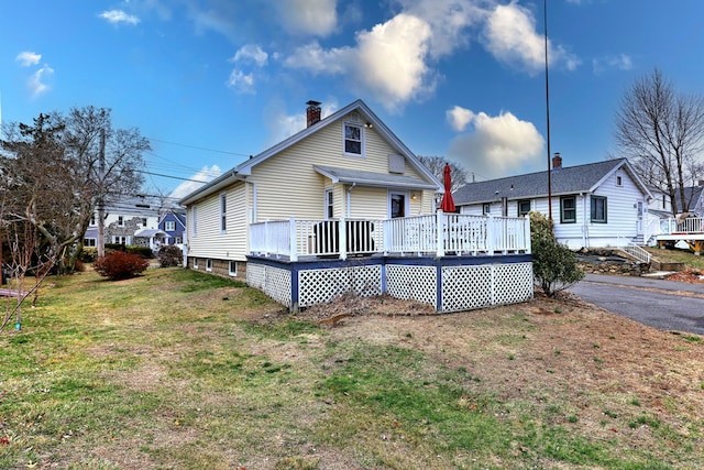 back of house with a chimney, a yard, and a wooden deck