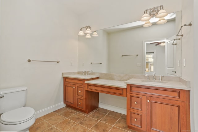 full bath featuring toilet, a sink, tile patterned floors, double vanity, and baseboards