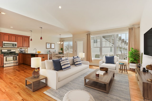 living area with recessed lighting, light wood finished floors, an inviting chandelier, and lofted ceiling
