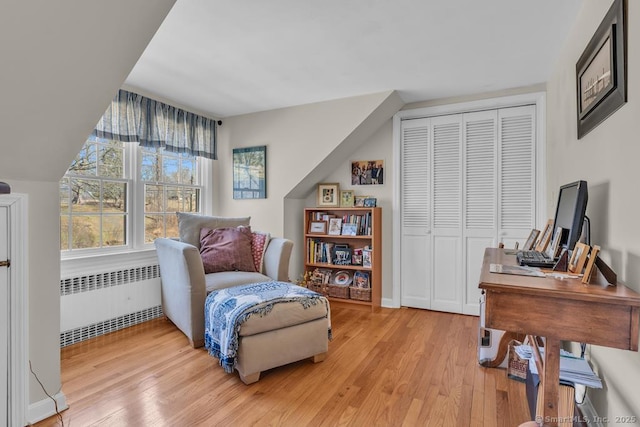 sitting room featuring radiator, light wood-style flooring, and baseboards