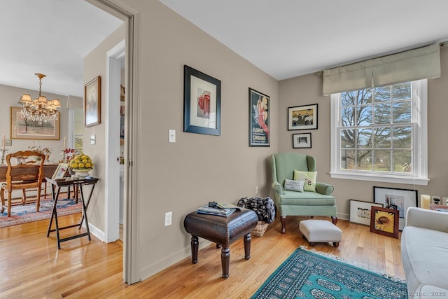 sitting room with light wood finished floors, baseboards, and a notable chandelier
