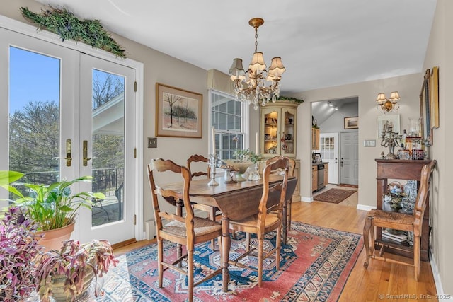 dining area featuring french doors, a notable chandelier, baseboards, and light wood finished floors