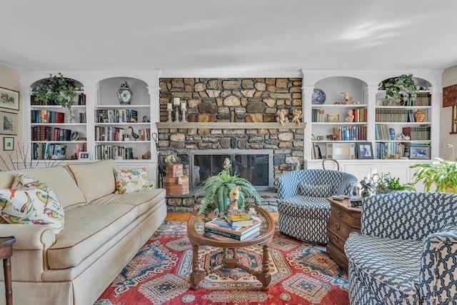 living room featuring a stone fireplace, wood finished floors, and ornamental molding