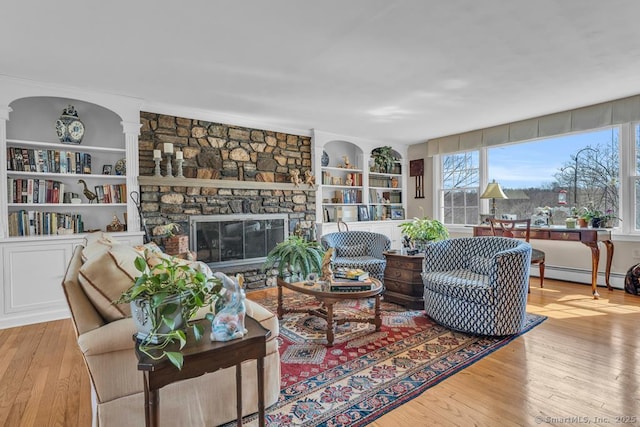 living room featuring wood-type flooring, a fireplace, plenty of natural light, and a baseboard radiator
