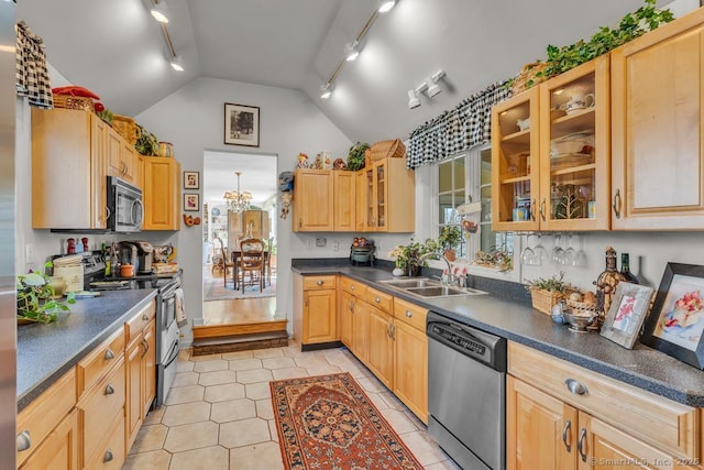 kitchen with dark countertops, appliances with stainless steel finishes, glass insert cabinets, a sink, and vaulted ceiling