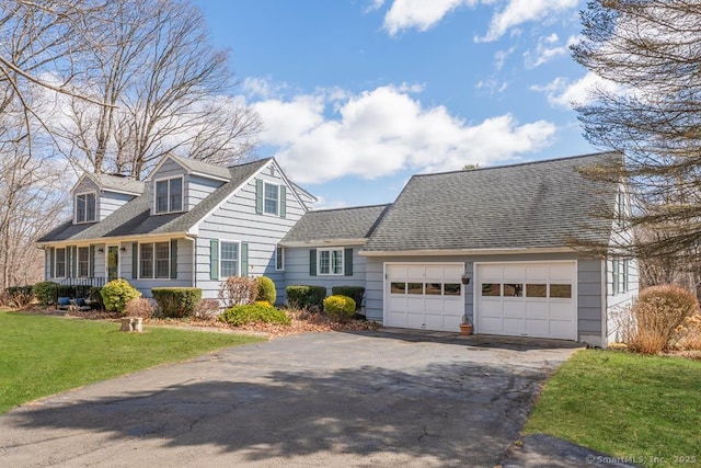 new england style home featuring a front yard, driveway, and an attached garage