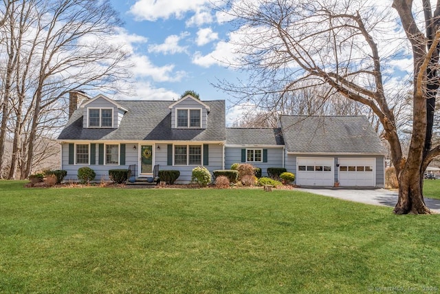 new england style home with an attached garage, a chimney, a front lawn, roof with shingles, and driveway
