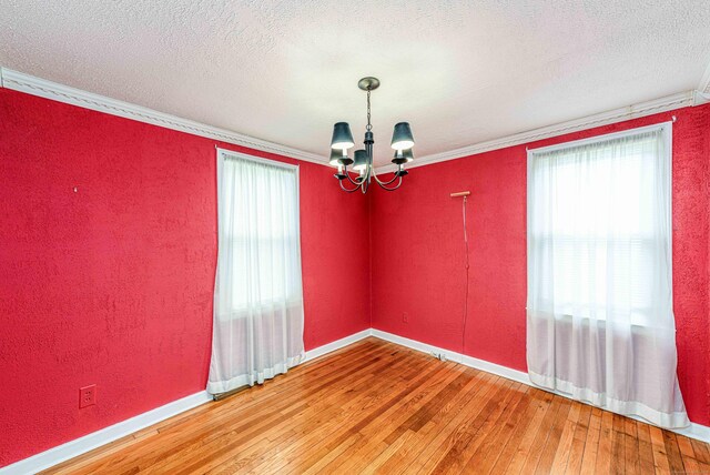95 Vista Dr, East Haven, CT 06512 - empty room featuring crown molding, an inviting chandelier, light wood finished floors, a textured ceiling, and baseboards