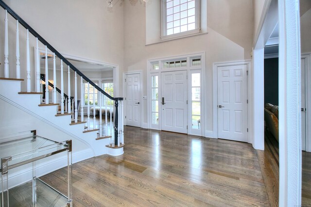 foyer with a high ceiling, baseboards, stairway, and wood finished floors