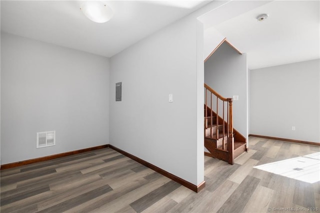 empty room featuring baseboards, stairs, visible vents, and wood finished floors