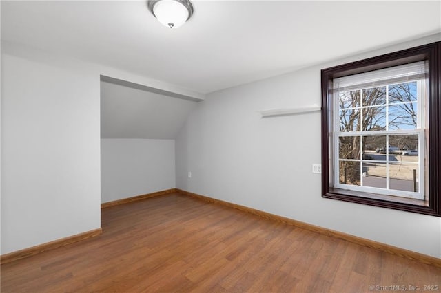 bonus room with baseboards, lofted ceiling, and wood finished floors
