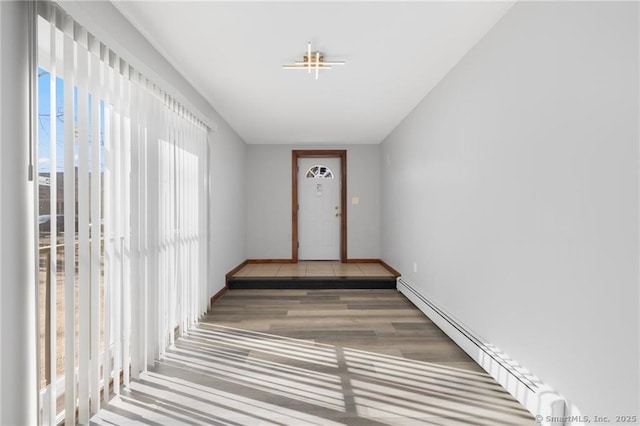 interior space featuring baseboards, wood finished floors, and a baseboard heating unit