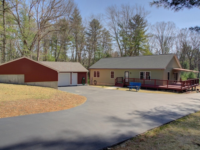 view of front facade featuring an outdoor structure, a wooden deck, driveway, and a detached garage