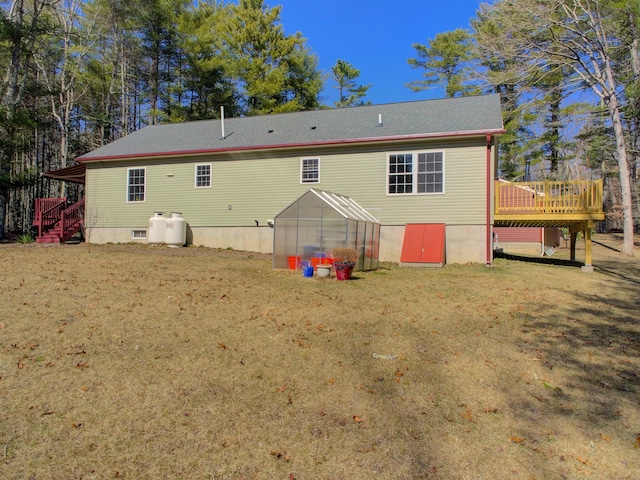 back of property with a greenhouse and a deck