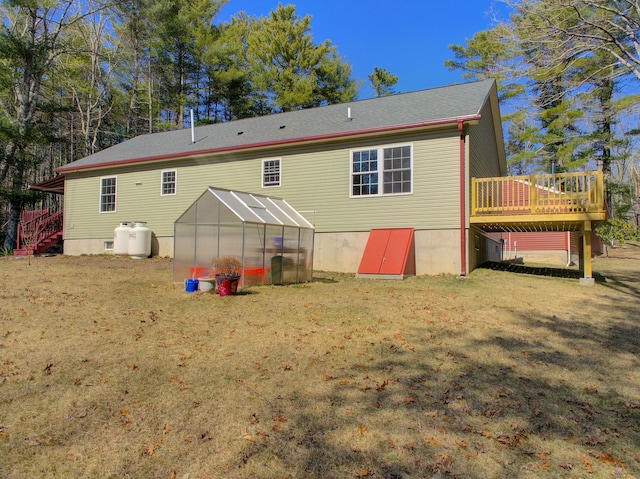 back of property with a deck, a yard, a greenhouse, an outbuilding, and stairway