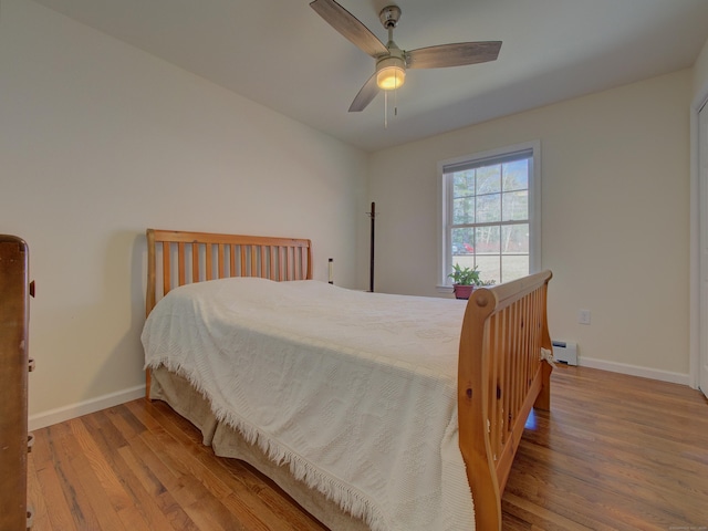 bedroom featuring baseboards, ceiling fan, wood finished floors, and baseboard heating