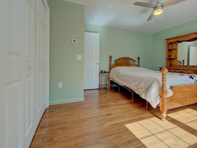 bedroom featuring baseboards, a ceiling fan, light wood-style flooring, and a closet