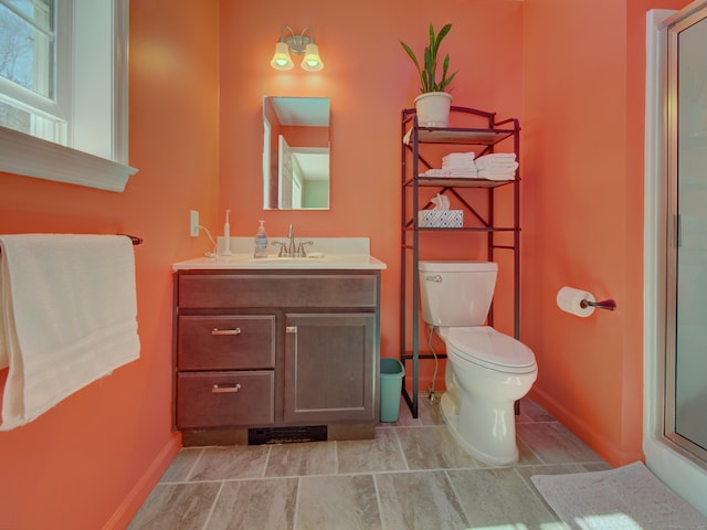 full bathroom featuring vanity, baseboards, an enclosed shower, and toilet