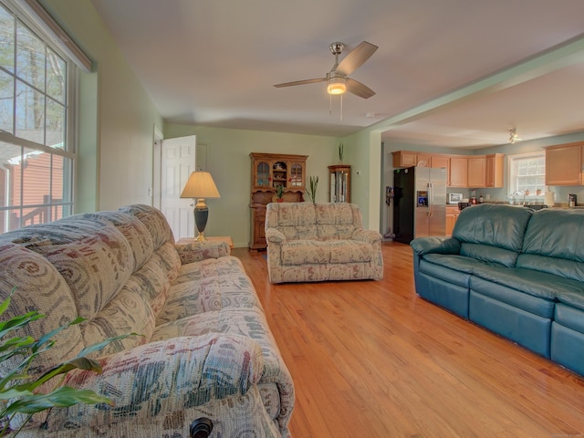 living area featuring light wood-type flooring and a ceiling fan