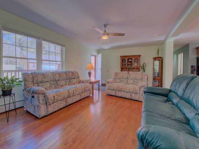 living area with a ceiling fan, wood finished floors, and baseboard heating