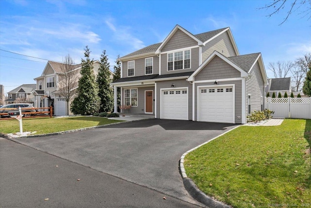 view of front facade with aphalt driveway, fence, and a front lawn