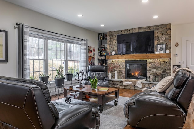 living room featuring a stone fireplace, wood finished floors, and recessed lighting