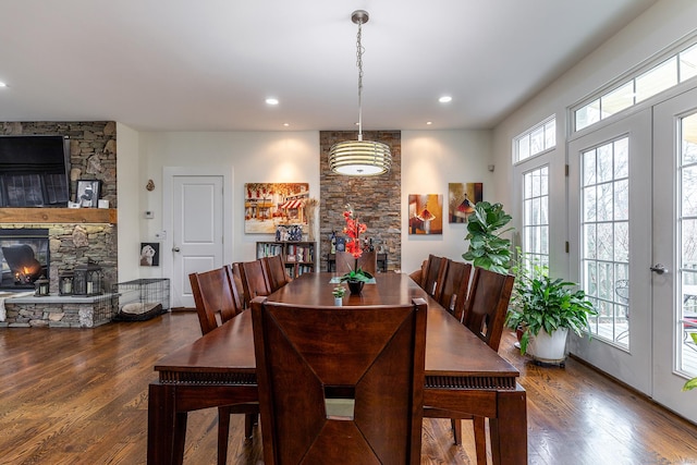 dining room featuring a stone fireplace, wood finished floors, and recessed lighting
