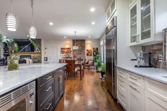 kitchen featuring tasteful backsplash, glass insert cabinets, white cabinetry, light stone counters, and built in appliances