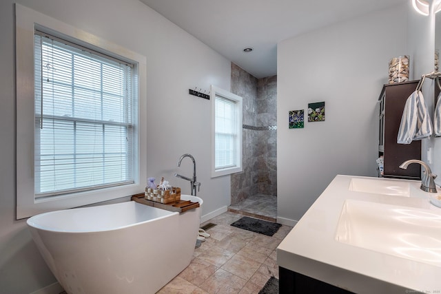bathroom with double vanity, a sink, baseboards, and walk in shower