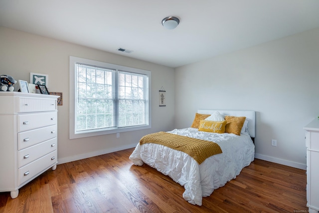 bedroom featuring visible vents, baseboards, and wood finished floors