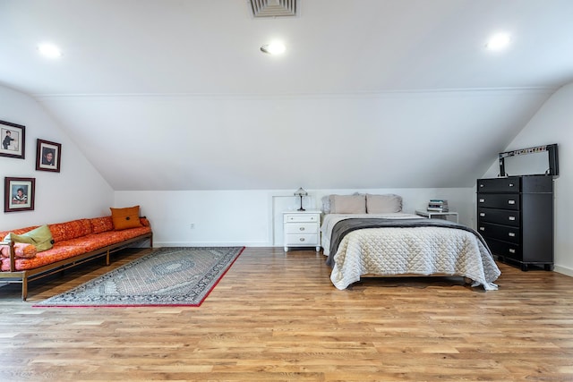 bedroom featuring baseboards, lofted ceiling, visible vents, and wood finished floors