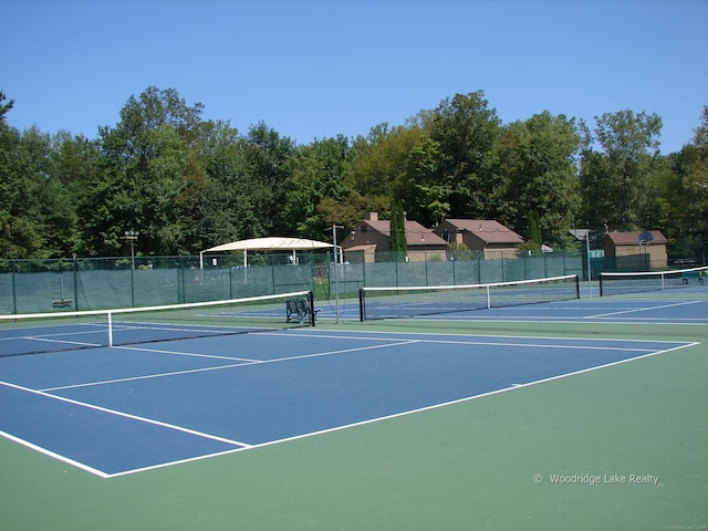 view of tennis court with community basketball court and fence