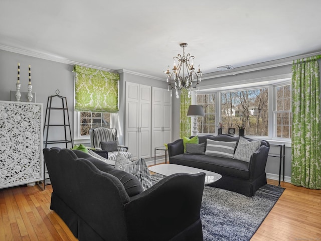 living room with an inviting chandelier, ornamental molding, hardwood / wood-style floors, and visible vents