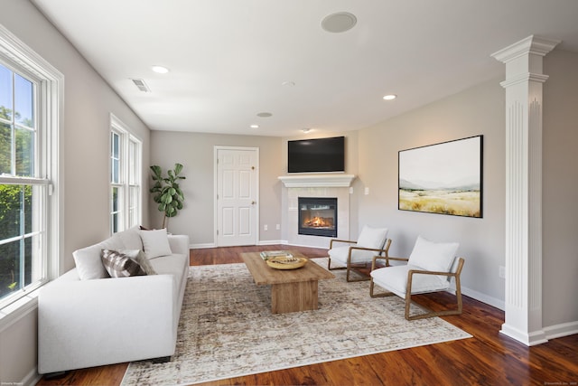 living area featuring wood finished floors, decorative columns, a fireplace, baseboards, and recessed lighting