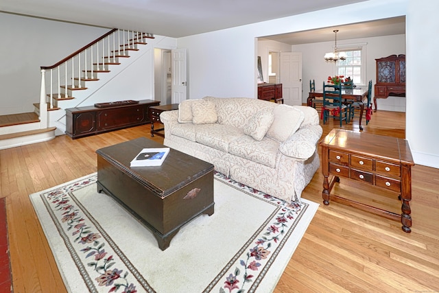 living room featuring stairs, an inviting chandelier, and hardwood / wood-style flooring