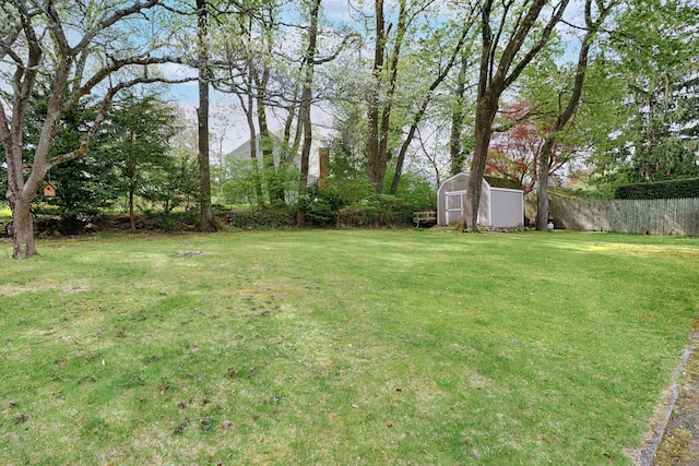 view of yard featuring a storage unit, fence, and an outbuilding