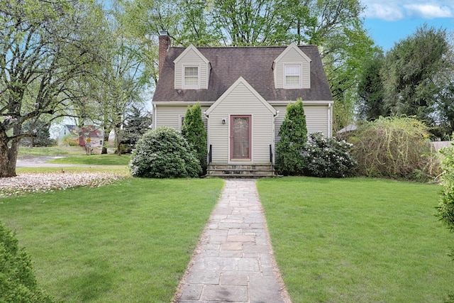 cape cod house with roof with shingles, a chimney, and a front lawn