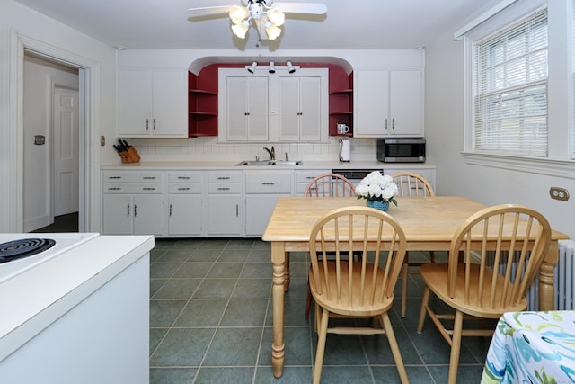 kitchen featuring stainless steel microwave, a sink, open shelves, and decorative backsplash