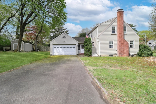 view of side of home with aphalt driveway, a storage unit, a chimney, an attached garage, and a lawn
