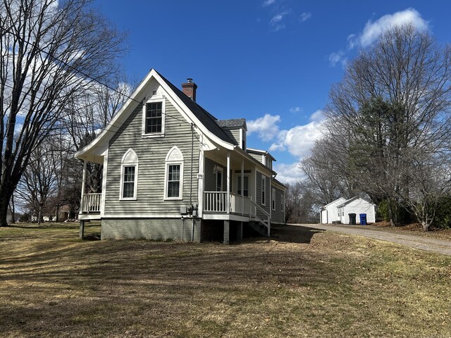 view of property exterior featuring a chimney, an outbuilding, and a porch