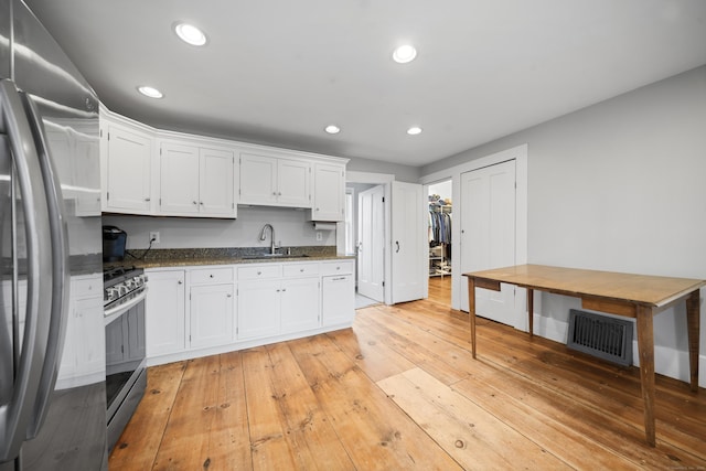 741 Mapleton Ave, Suffield, CT 06078 - kitchen with stainless steel appliances, white cabinetry, dark stone countertops, light wood-style floors, and recessed lighting